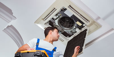 Home hvac worker repairing unit on ladder